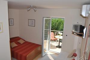 Schlafzimmer mit einem Bett, einem TV und einem Balkon in der Unterkunft Apartments with a parking space Omisalj, Krk - 12793 in Omišalj