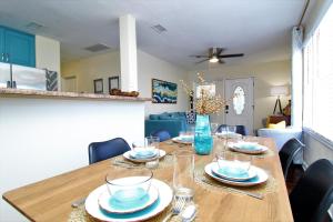 una mesa de comedor con platos y vasos. en Beachy Bungalow for Family Fun! Walk to beach! en Pensacola