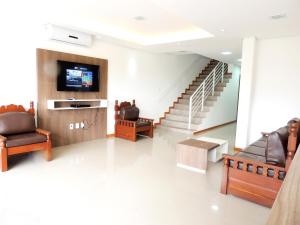 a living room with chairs and a tv and stairs at Pousada Molhes da Barra in Torres
