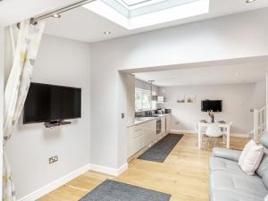 a living room with a couch and a tv on the wall at The Beach House in Crantock