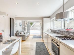a kitchen with white countertops and a living room at The Beach House in Crantock