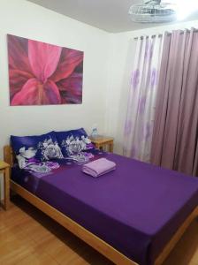 a bedroom with a purple bed with a painting on the wall at CANIBAD SECRET PARADISE RESORT in Aumbay