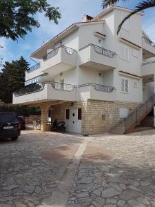 ein großes weißes Gebäude mit Balkon und Parkplatz in der Unterkunft Apartments by the sea Novalja, Pag - 13033 in Novalja