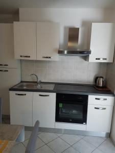 eine Küche mit weißen Schränken und einem schwarzen Gerät in der Unterkunft Apartments by the sea Novalja, Pag - 13033 in Novalja