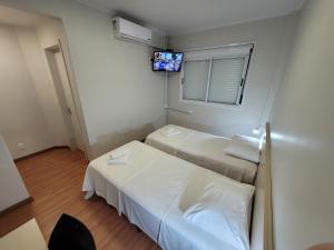 a small room with two beds and a tv at Pousada dos Frades in Garibaldi