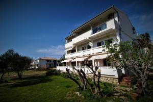 a white building with a yard in front of it at Double Room Pag 13060a in Pag