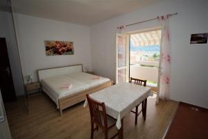 1 dormitorio con cama, mesa y ventana en Apartments and rooms with parking space Pag - 13060 en Pag