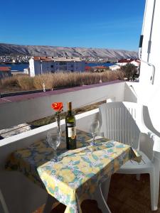 a table with a bottle of wine and glasses on a balcony at Apartments and rooms with parking space Pag - 13060 in Pag