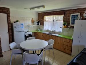 cocina con mesa blanca y nevera blanca en Ocean Beach Chalet 16, en Jurien Bay