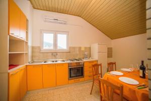 a kitchen with orange cabinets and a table with chairs at Apartments with parking space Bol, Brac - 12980 in Bol