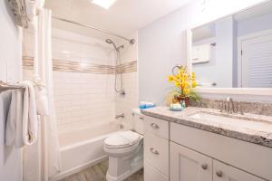 a white bathroom with a tub and a toilet and a sink at Remodeled 1BR Condo, Steps to Beach, Free Parking! in Honolulu