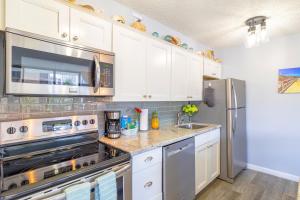 a kitchen with stainless steel appliances and white cabinets at Remodeled 1BR Condo, Steps to Beach, Free Parking! in Honolulu