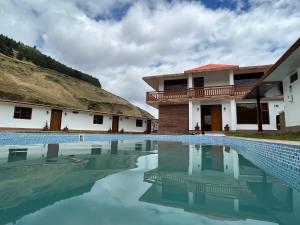 una piscina frente a una casa con techo de paja en San Martin Resort, 