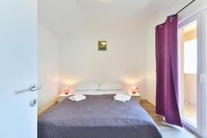 een slaapkamer met een bed met paarse gordijnen bij Apartments by the sea Nin, Zadar - 13172 in Nin
