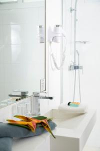 a white bathroom with a sink and a shower at Hotel Beaurivage in Noumea