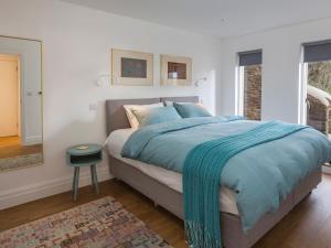 um quarto com uma cama com um cobertor azul em The Bothy em Slapton
