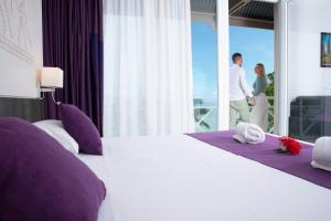 a man and a woman standing in a bedroom with a bed at Hotel Beaurivage in Noumea