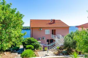 a pink house with stairs in front of the water at Apartments by the sea Karbuni, Korcula - 13217 in Prizba