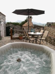 a hot tub with a table and chairs and an umbrella at Secluded house with a parking space Tomislavovac, Peljesac - 13280 in Putniković