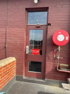 una puerta roja en un edificio de ladrillo con un cartel en él en Royal Derby Hotel en Melbourne