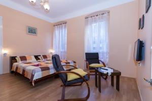 a bedroom with a bed and chairs and a television at Apartments by the sea Rijeka - 13293 in Rijeka