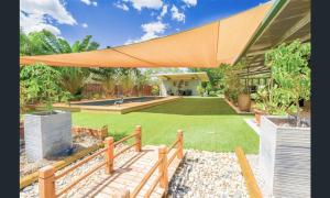a backyard with a lawn with a large orange umbrella at Almost Off Grid Tranquillity in Katherine