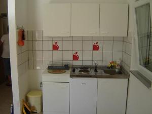 a kitchen with white cabinets and an apple on the wall at Apartments by the sea Brgulje, Molat - 13318 in Molat