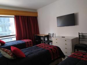 a bedroom with two beds and a dresser and a television at Espectacular departamento a una cuadra del obelisco (Microcentro) in Buenos Aires +22 photos