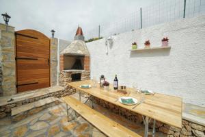 un patio con una mesa de madera y un horno de pizza en Family friendly apartments with a swimming pool Bol, Brac - 13364 en Bol