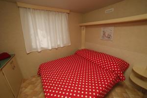 a bedroom with a red bed with a white polka dot blanket at Family friendly apartments with a swimming pool Bol, Brac - 13364 in Bol