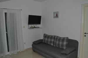 uma sala de estar com um sofá e uma televisão de ecrã plano em Apartments with a parking space Grebastica, Sibenik - 13365 em Bašelovići