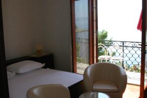 1 dormitorio con 1 cama y 2 sillas y balcón en Apartments and rooms by the sea Puntinak, Brac - 12255, en Selca