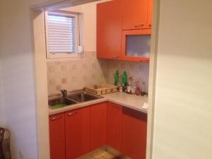 Elle comprend une petite cuisine avec des placards rouges et un évier. dans l'établissement Apartments by the sea Muline, Ugljan - 12533, à Ugljan