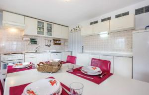 eine Küche mit einem Tisch mit roten Stühlen und weißen Schränken in der Unterkunft Apartments with a parking space Kastav, Opatija - 13441 in Kastav