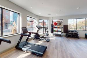 einen Fitnessraum mit Laufbändern und Crosstrainern in einem Zimmer mit Fenstern in der Unterkunft Beautiful 2BR Apt/EWR Airport/King /Free Parking in Newark