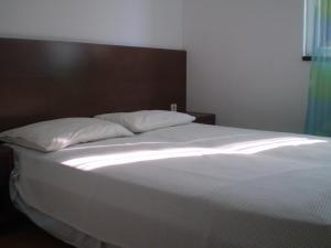 un letto con lenzuola e cuscini bianchi in una camera da letto di Apartments by the sea Bol, Brac - 13539 a Bol