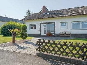 uma casa com uma cerca de madeira e um banco em A detached holiday home in a highly scenic area em Trierscheid