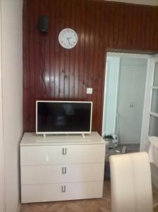 a television on a dresser with a clock on the wall at Apartments with a parking space Kostrena, Rijeka - 13563 in Kostrena