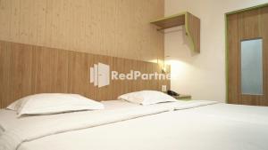 a large bed with white sheets and pillows at Wisma Sederhana Mitra RedDoorz in Medan