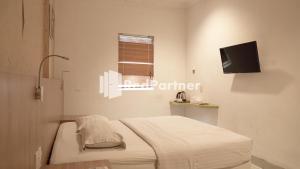 a small bedroom with a bed and a television at Wisma Sederhana Mitra RedDoorz in Medan