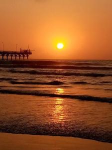 a sunset on the beach with a pier in the ocean at Departamentos Cerro Azul P2 in Cerro Azul