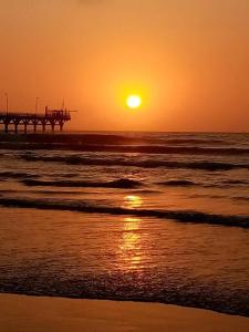 a sunset on the beach with a pier in the ocean at Departamentos Cerro Azul P2 in Cerro Azul +11 photos