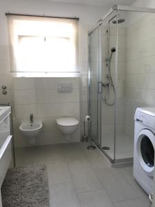 a bathroom with a shower toilet and a washing machine at Apartments with a swimming pool Kastav, Opatija - 13638 in Kastav