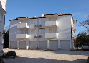 a large white building with two garage doors at Apartments with a parking space Rogoznica - 13684 in Rogoznica