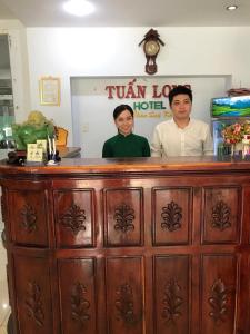 胡志明市的住宿－Tuan Long Hotel，站在酒吧后面的男人和女人