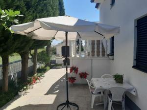 una sombrilla blanca en un patio con mesa y sillas en Apartments with a parking space Sabunike, Zadar - 14574 en Nin