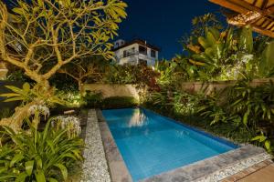 a swimming pool in the middle of a garden at night at Gora House Bali in Ubud