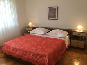 een slaapkamer met een bed met een rode deken en 2 lampen bij Apartments with a parking space Kali, Ugljan - 14590 in Kali