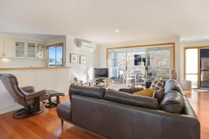 a living room with a brown leather couch and chairs at LAKESIDE2 in Merimbula