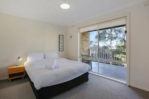 a bedroom with a large bed and a large window at LAKESIDE2 in Merimbula